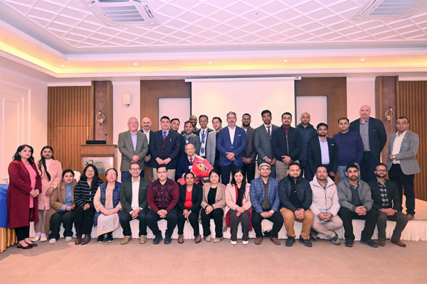 A large group of medical professionals posing for a group photo in a formal indoor event space with wood paneling.