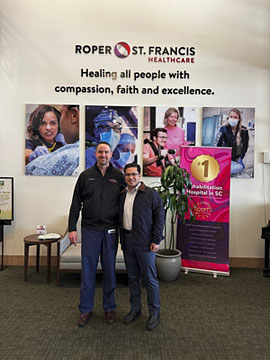 Two men posing inside the lobby of Roper St. Francis Healthcare.