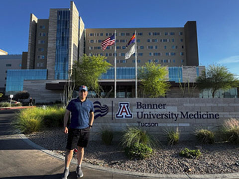 A man standing in front of the Banner University Medicine Tucson hospital entrance sign.