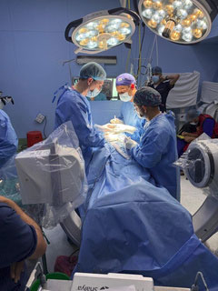 Surgical team performing an operation under bright surgical lights in an operating room.