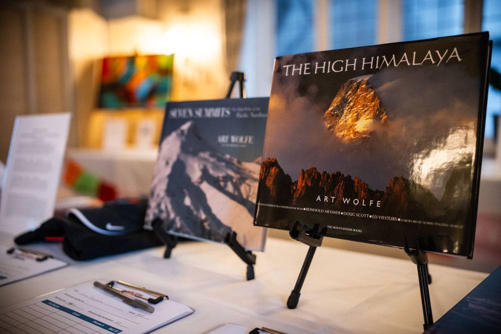 Close-up of photography books titled "The High Himalaya" and "Seven Summits" displayed on easels at an event.